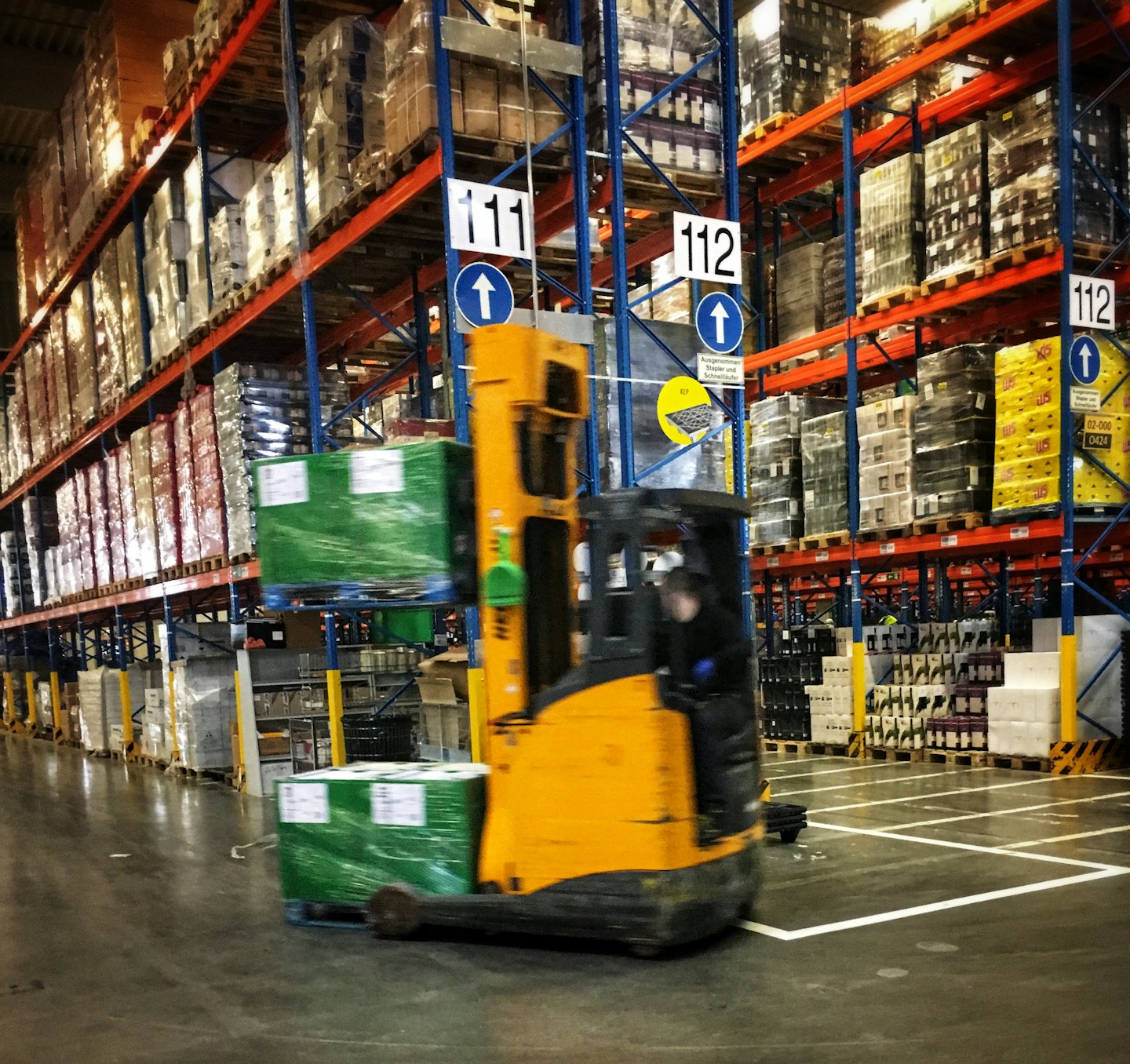 Carretilla elevadora moviendo un palé en un almacén grande.